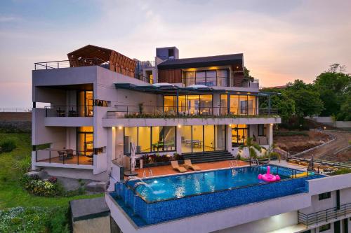 a house with a swimming pool in front of it at Pearl Lakeview Mansion by StayVista - Lakeside villa with Infinity pool, Jacuzzi, In-house theatre & Games room in Igatpuri