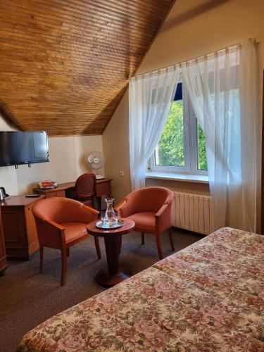 a hotel room with two beds and a table and chairs at Vila Florena Garden in Palanga
