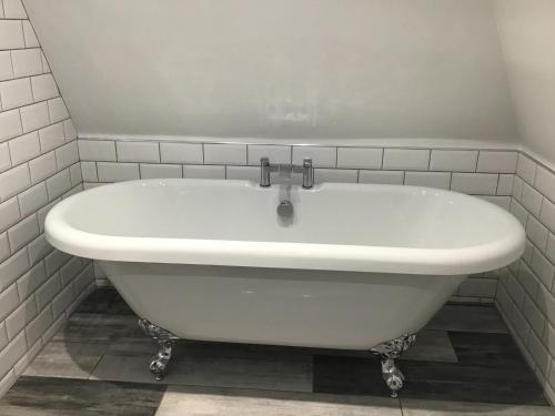 a white bath tub in a white tiled bathroom at Dyserth Waterfalls apartment in Dyserth