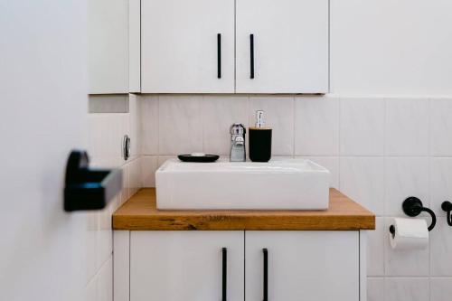 una cocina con fregadero blanco y armarios blancos en Sweet 1BR Studio In St Kilda, en Melbourne