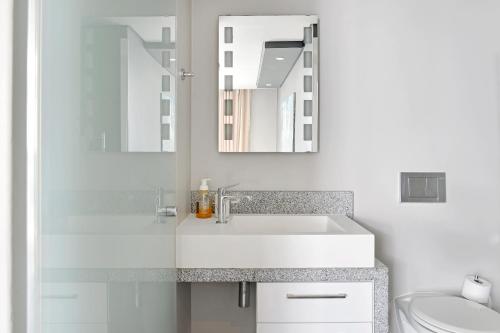 Baño blanco con lavabo y espejo en The Legacy 104, en Ciudad del Cabo