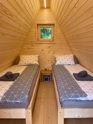2 Betten in einem Blockhaus mit Fenster in der Unterkunft Glamping Grintovec 