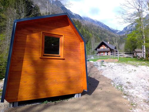 a small wooden cabin with a window on a mountain at Glamping Grintovec 