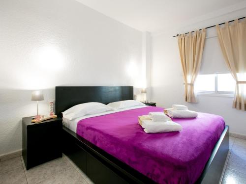 una camera da letto con un letto viola e due asciugamani di 206 Los Angeles ad Arona