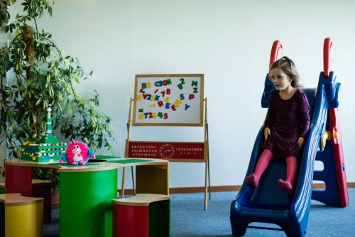 a little girl riding on a slide in a play room at Hotel Sanvilla in Sigulda