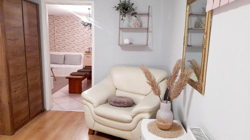 a living room with a white chair and a mirror at Apartment Eleco in Bjelovar