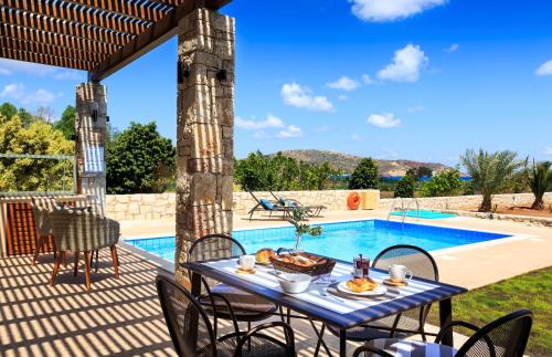 un patio avec une table et des chaises à côté d'une piscine dans l'établissement Muses Beach Villas - Cleo, à Siteía