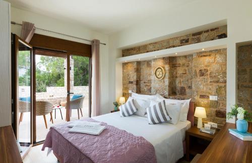 a bedroom with a bed and a stone wall at Muses Beach Villas - Erato in Sitia