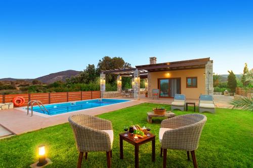 a yard with chairs and a pool and a house at Muses Beach Villas - Erato in Sitia