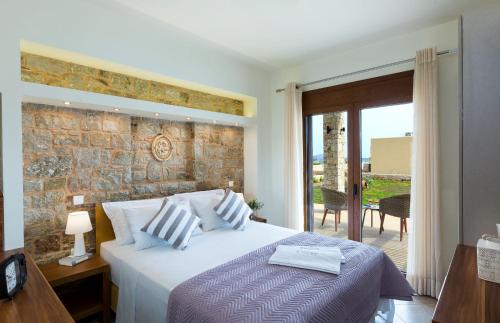 una camera con letto e parete in pietra di Muses Beach Villas - Thalia a Sitia