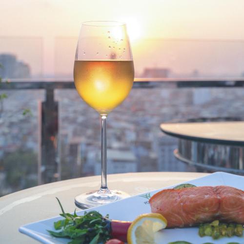 a glass of wine sitting on a table with a plate of food at Poulo Wai Hotel & Apartment in Phnom Penh