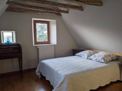 a bedroom with a bed and a table and a window at LE PARDÈS BnB in Rocamadour