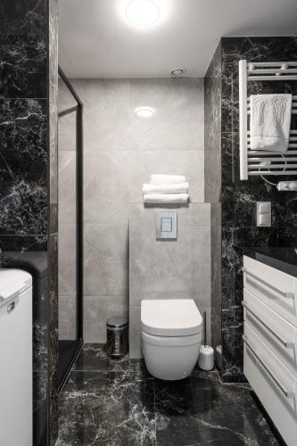 a black and white bathroom with a toilet and towels at RentPlanet - Apartamenty Zarembowicza II in Wrocław