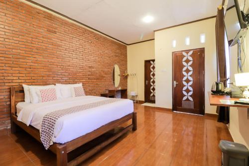 um quarto com uma cama e uma parede de tijolos em Hotel Ndalem Ayem Syariah em Magelang