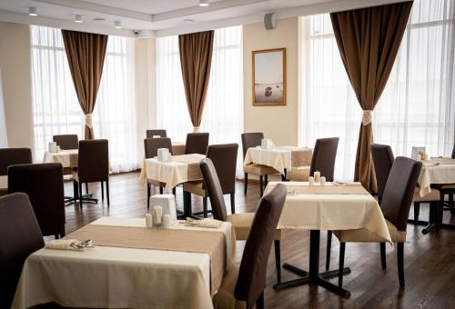 un ristorante con tavoli e sedie bianchi e finestre di Chagala Bautino Hotel a Bautino