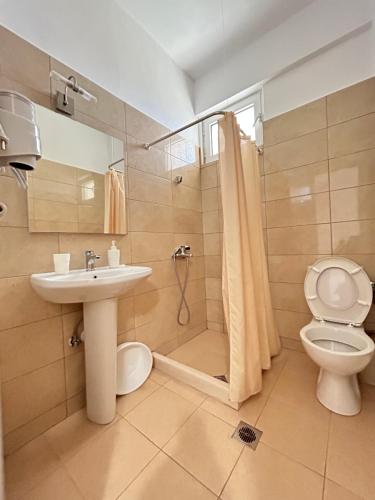 a bathroom with a sink and a toilet and a shower at Koks’ Guesthouse in Himare