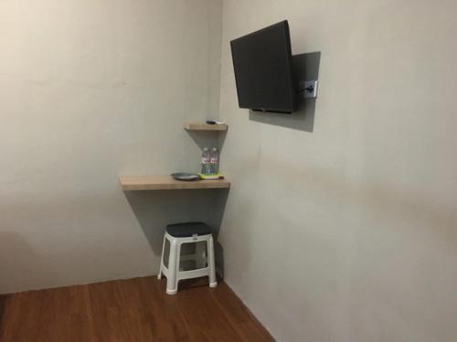 a room with a desk and a tv and a stool at Royal Guesthouse Bandar Lampung in Bandar Lampung