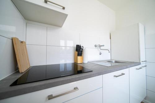 uma cozinha branca com um lavatório e armários brancos em Favorite Stays - Suite And More - Neuss em Neuss