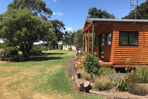 Cabaña de madera pequeña con césped y árboles en Colac Otway Caravan & Cabin Park, en Colac