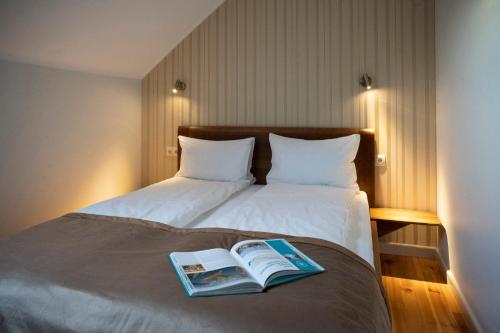Una cama con un libro encima. en Villa ACACIA en Kaunas