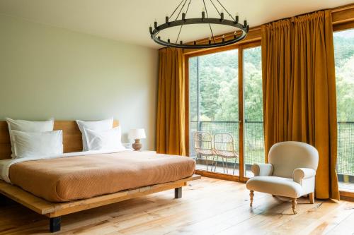 ein Schlafzimmer mit einem Bett und einem Stuhl sowie einem großen Fenster in der Unterkunft Rooms Hotel Kazbegi in Kazbegi