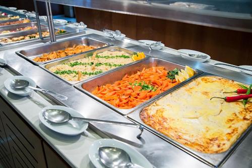 a buffet with several trays of food on a table at Crystal Springs Beach Hotel in Protaras