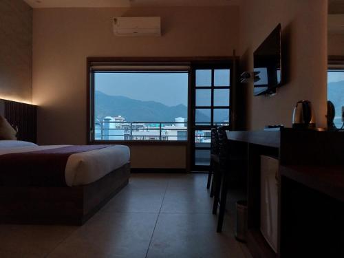a hotel room with a bed and a large window at Dreamy Desert Hotel in Haldwāni