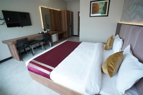 a bedroom with a bed and a desk and a television at Dreamy Desert Hotel in Haldwāni