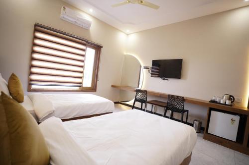 a hotel room with two beds and a tv at Dreamy Desert Hotel in Haldwāni