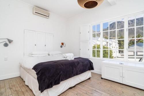 a white bedroom with a bed and a large window at Light Filled Spacious 1 Bedroom Haven in Cape Town