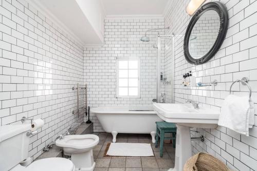 a white bathroom with a tub and a toilet and a sink at Light Filled Spacious 1 Bedroom Haven in Cape Town