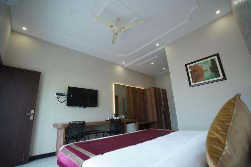 a bedroom with a bed and a desk and a television at Dreamy Desert Hotel in Haldwāni