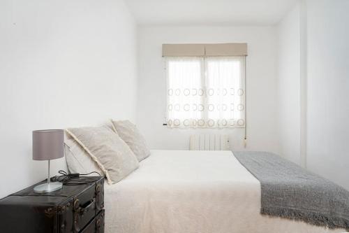 a white bedroom with a bed and a window at MyHouseSpain - Único piso cerca de la playa in Gijón