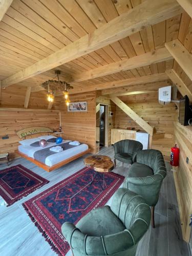 a bedroom with a bed and a couch and chairs at ELVA BUNGALOV in Çamlıhemşin