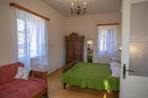 um quarto com uma cama verde e um sofá em Authentic house and traditional breakfast em Vrisnik