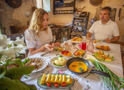 Un uomo e una donna seduti a un tavolo con del cibo di Terra Arhaica - Authentic house and traditional breakfast a Vrisnik