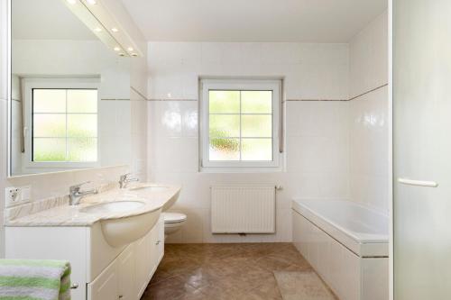 La salle de bains blanche est pourvue d'un lavabo, d'une baignoire et de toilettes. dans l'établissement Ferienhaus Lienz, à Lienz