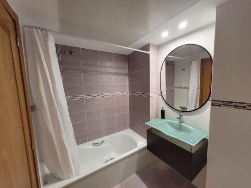 een badkamer met een bad, een wastafel en een spiegel bij Apartamento Margalló con Garaje in Xilxes
