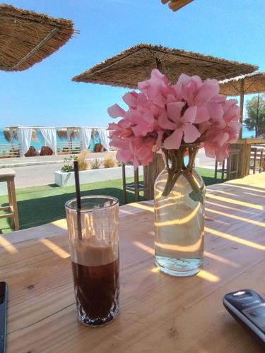 a vase with pink flowers and a drink on a table at Larissa in Skala