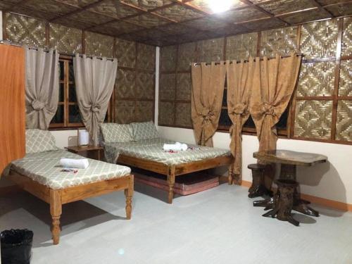 a room with two beds and a table and curtains at Caminres Homestay in Bug-ong
