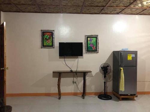 a room with a desk and a television and a table at Caminres Homestay in Bug-ong