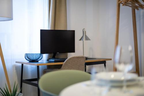 a room with a desk with a computer monitor and chairs at Arbio I Central Apartments Koblenz in Koblenz