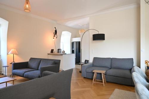 a living room with two blue couches and a kitchen at Osteiner Hof by The Apartment Suite in Mainz