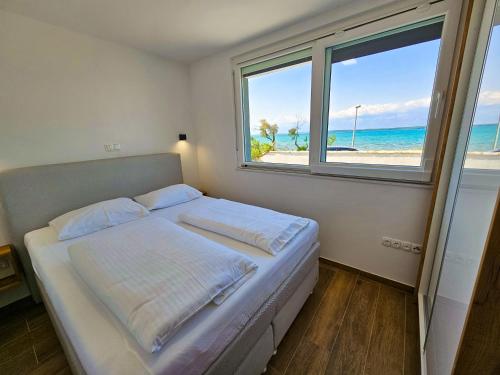 a bedroom with a bed with a view of the beach at Apartmani Adria in Nin