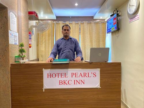 a man standing at a hotel perimeters big inn sign at Hotel Pearl's BKC Inn- Near Trade Centre, Visa Consulate in Mumbai