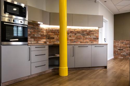 um poste amarelo numa cozinha com uma parede de tijolos em ORKANA House em Olsztyn