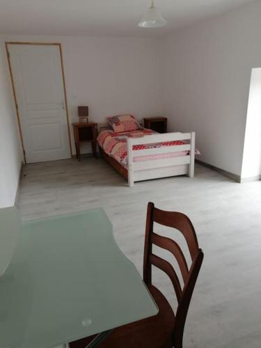 a bedroom with a bed and a table and a chair at Maison de campagne in Saint-Jouan-de-lʼIsle