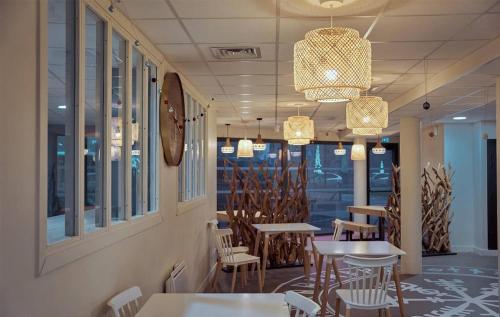 une salle à manger avec des tables, des chaises et des lustres dans l'établissement UXCO Uppehalls, à Le Petit-Quevilly