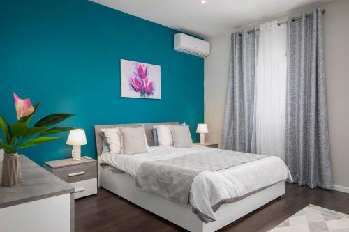 ein blaues Schlafzimmer mit einem Bett und einer blauen Wand in der Unterkunft Spacious Luxury 3BR Apartment with Terrace & Open Views - Zurrieq, close to sea in Żurrieq