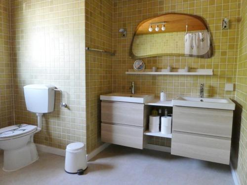 a bathroom with a toilet and two sinks and a mirror at Ferienwohnung WällerAuszeit in Bach